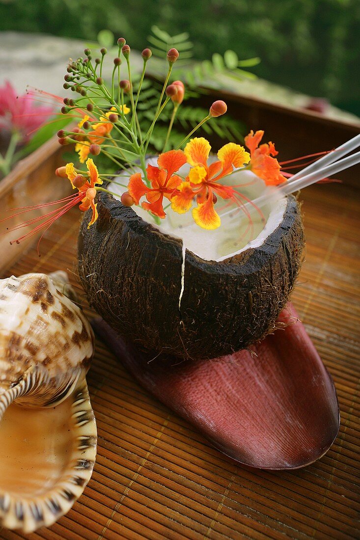 A Coconut Cocktail Served in a Coconut Shell with Flowers