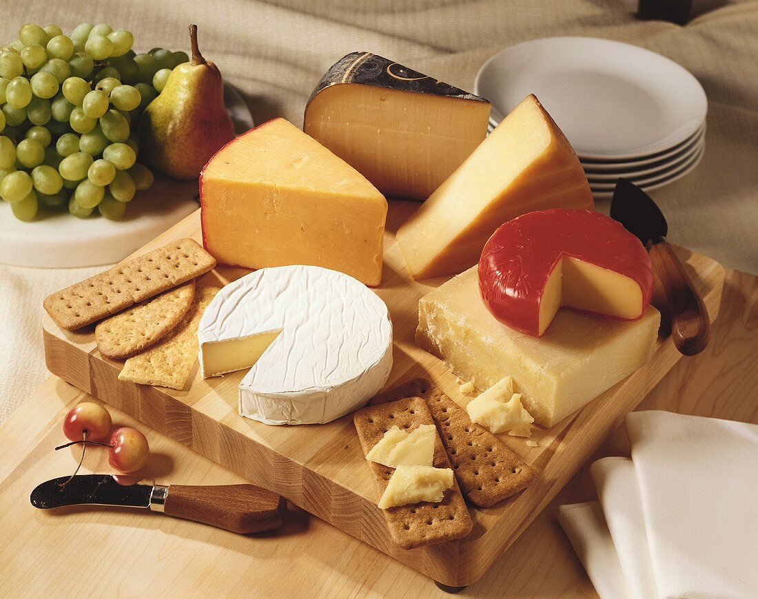 Cheese and crackers on a wooden board with fresh fruit