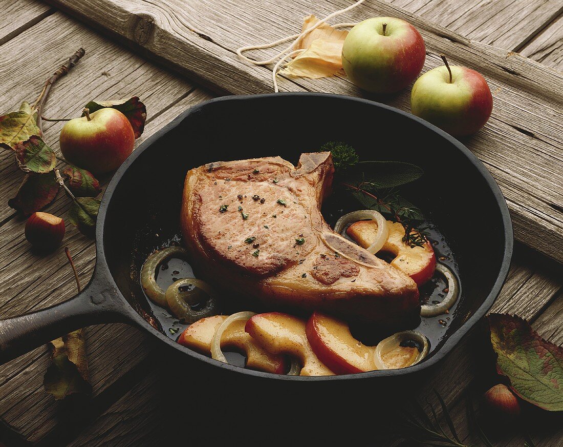 A Pork Chop with Apples and Onions in a Skillet