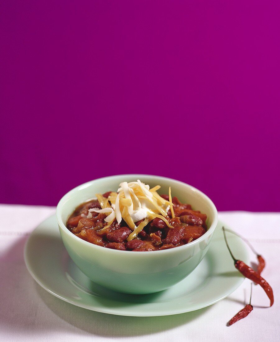A bowl of chili with cheese and sour cream