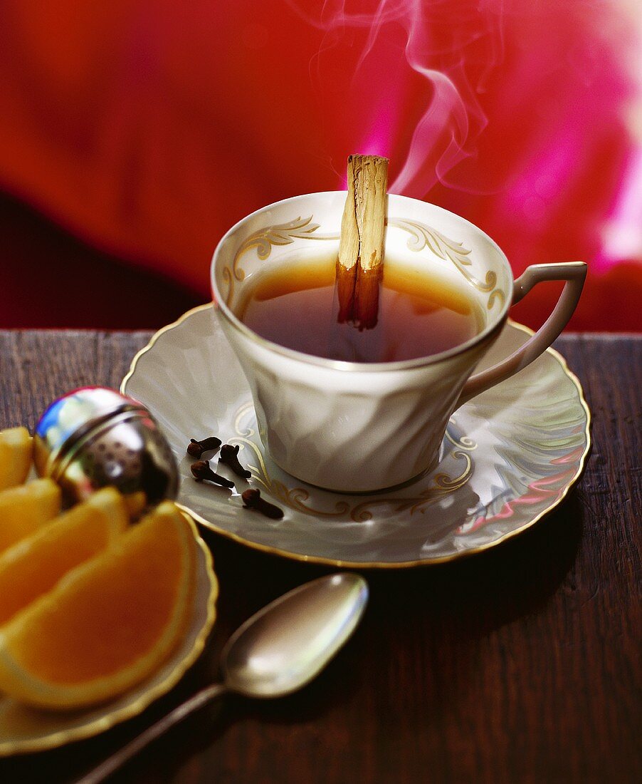 A Cup of Tea with Cloves, a Cinnamon Stick and Lemon Wedges