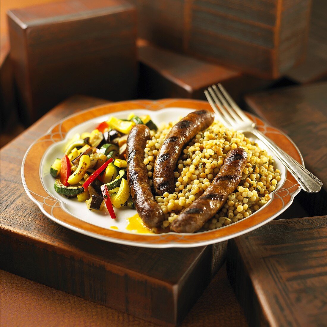 Serving of Merguez Sausage Over Israeli Couscous Served with Vegetable Medley