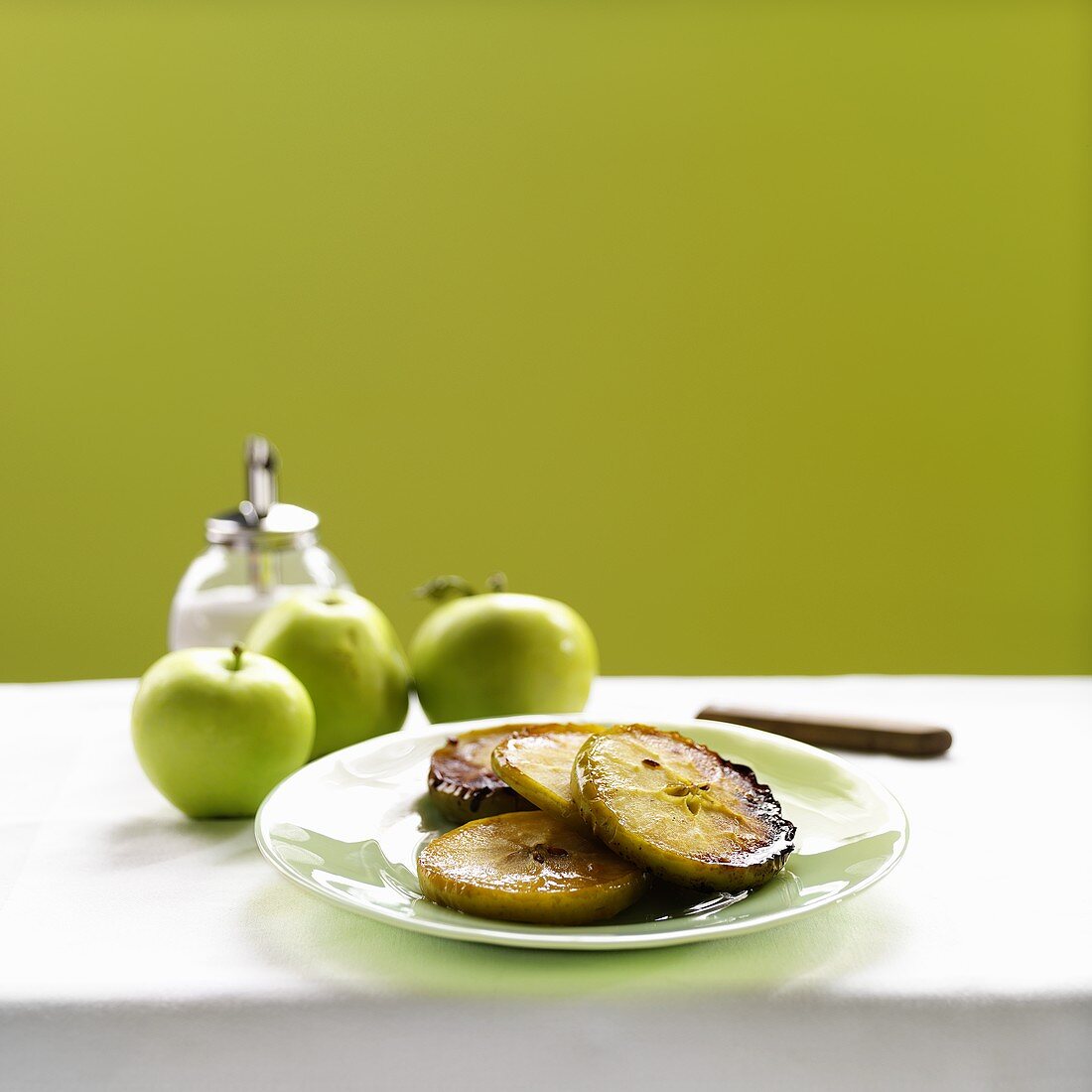Slices of Baked Apple on a Plate with Fresh Whole Apples