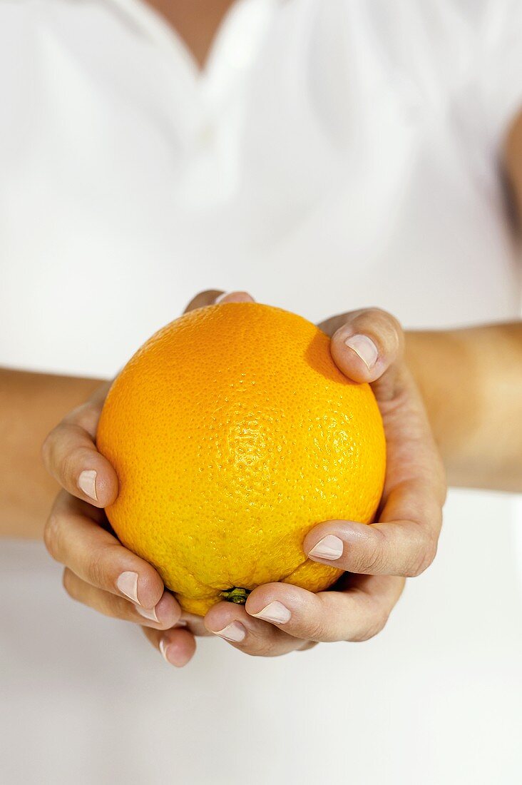 Close Up of Female Hands Holding a Whole Orange