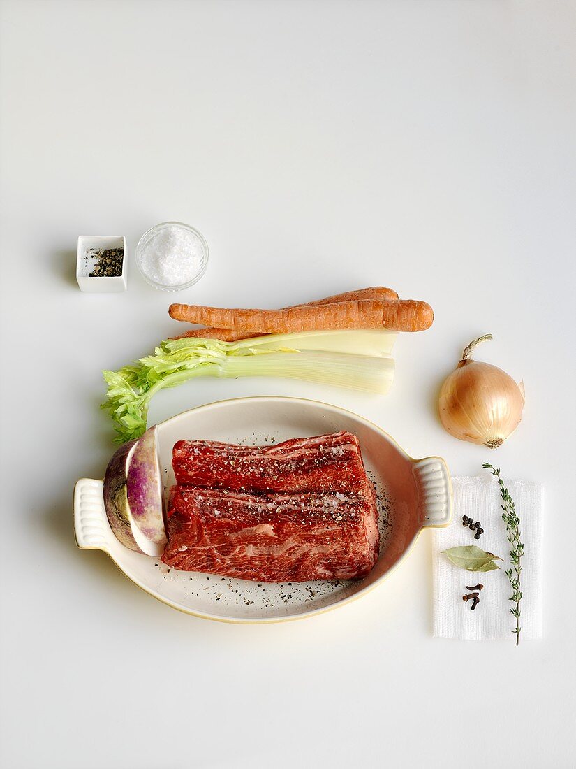 Raw Beef Roast in a Baking Dish with Raw Vegetables and Spices