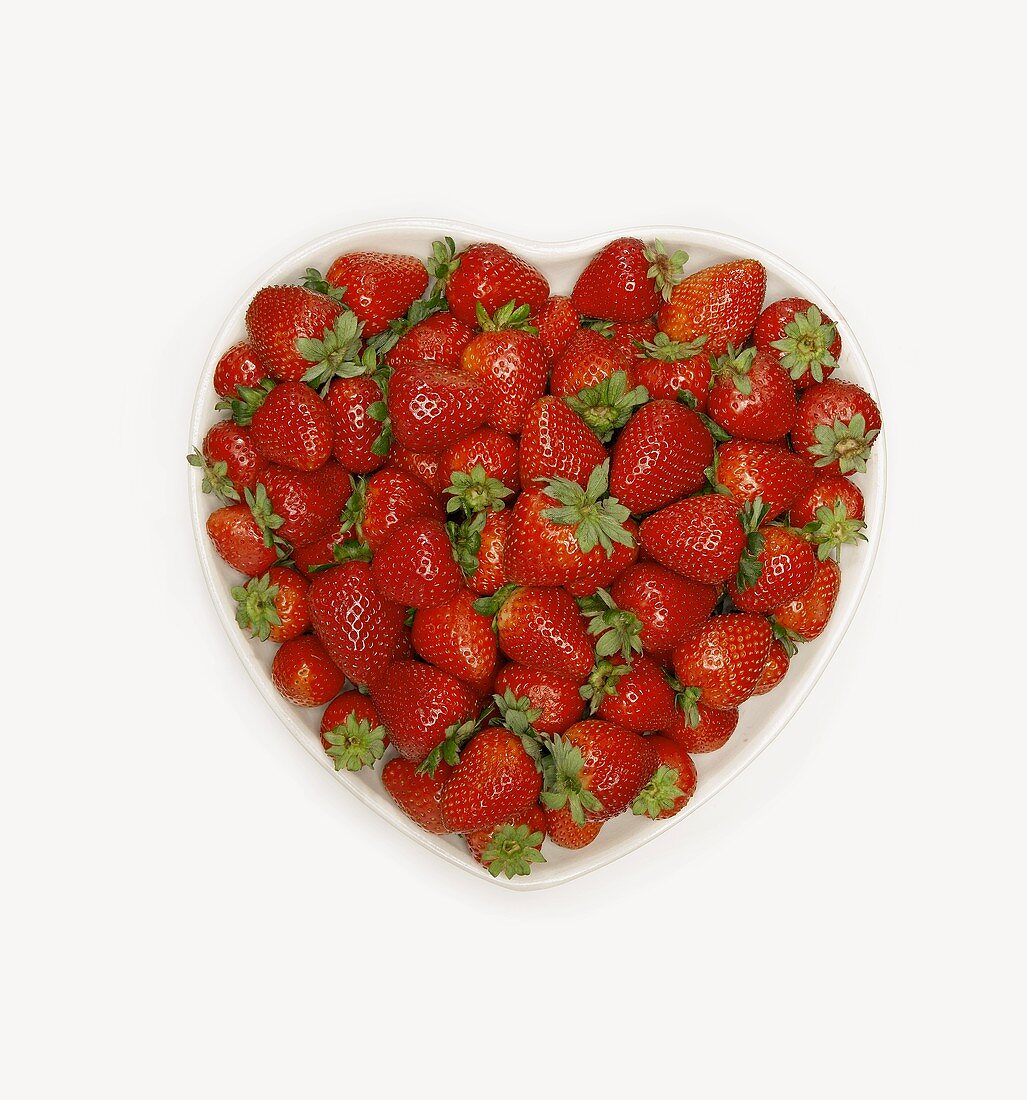 Overhead of Fresh Strawberries in White Heart Shaped Bowl; White Background