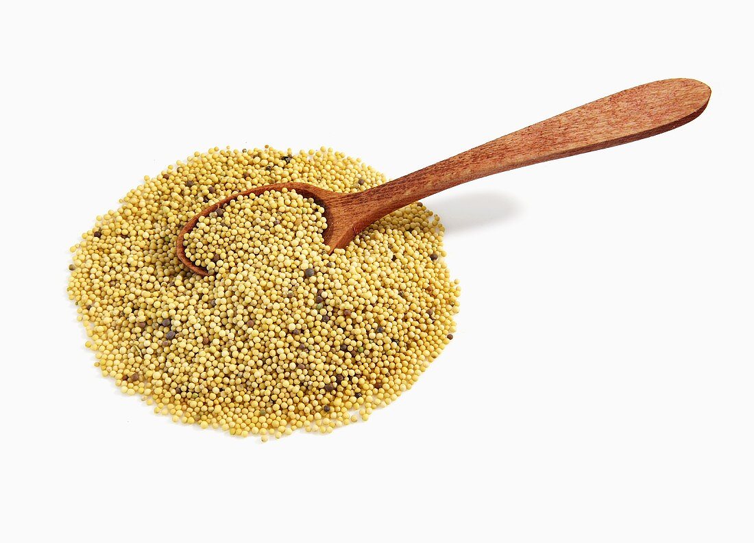 Pile of Mustard Seeds with Wooden Spoon on White Background