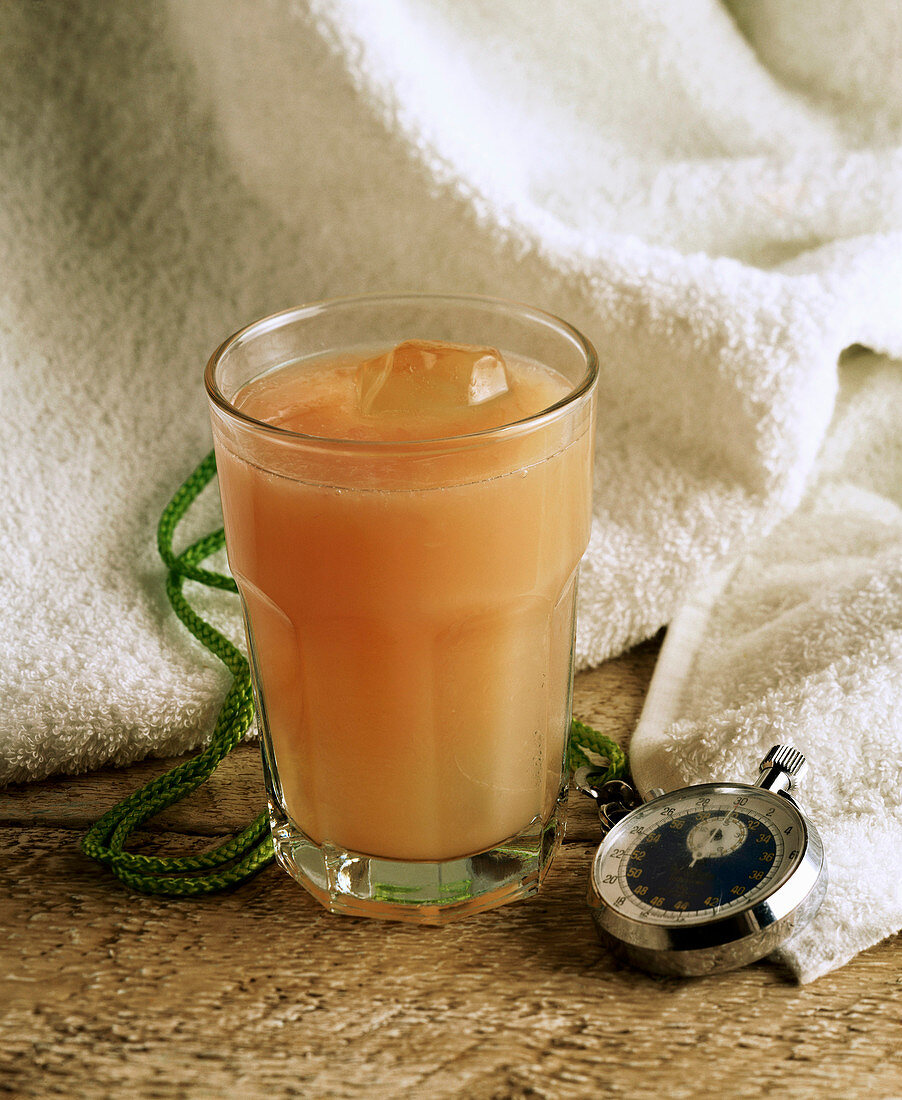 Glass of Healthy Grapefruit Juice on Ice; Stopwatch and Towel