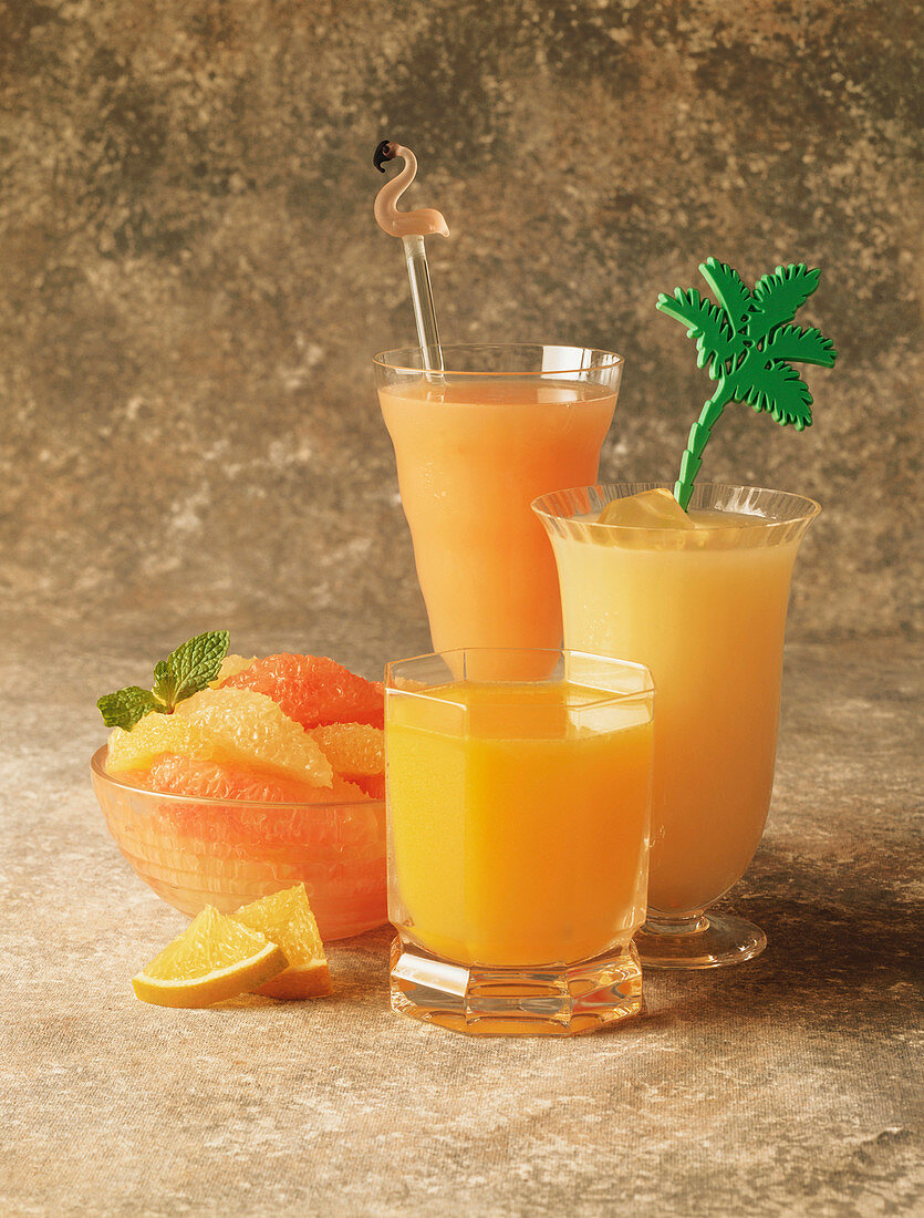 Three Assorted Glasses of Citrus Juice; Bowl of Grapefruit Slices and Orange Wedges