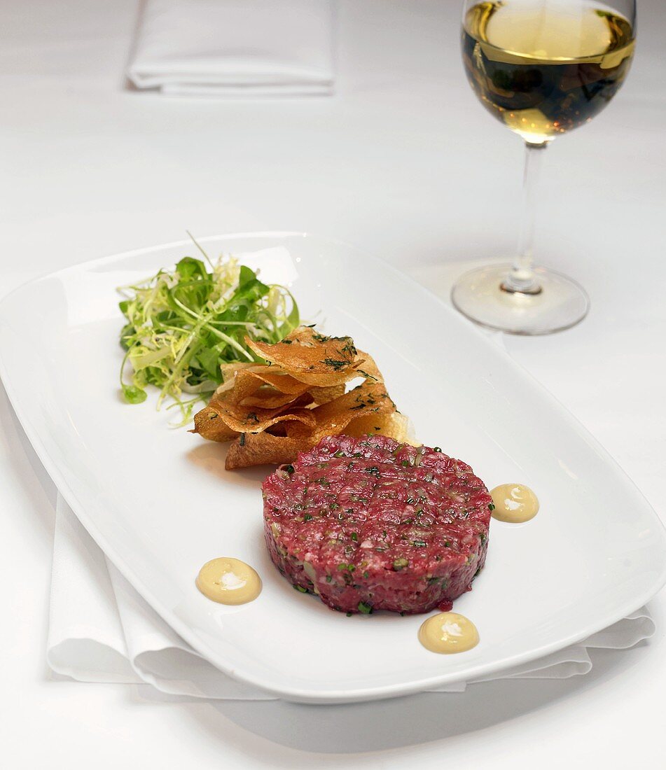 Serving of Steak Tartar with Mixed Greens on a White Plate