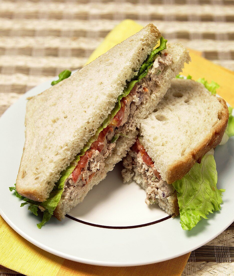 Tuna Salad Sandwich with Tomato and Lettuce Sliced in Half on White Plate