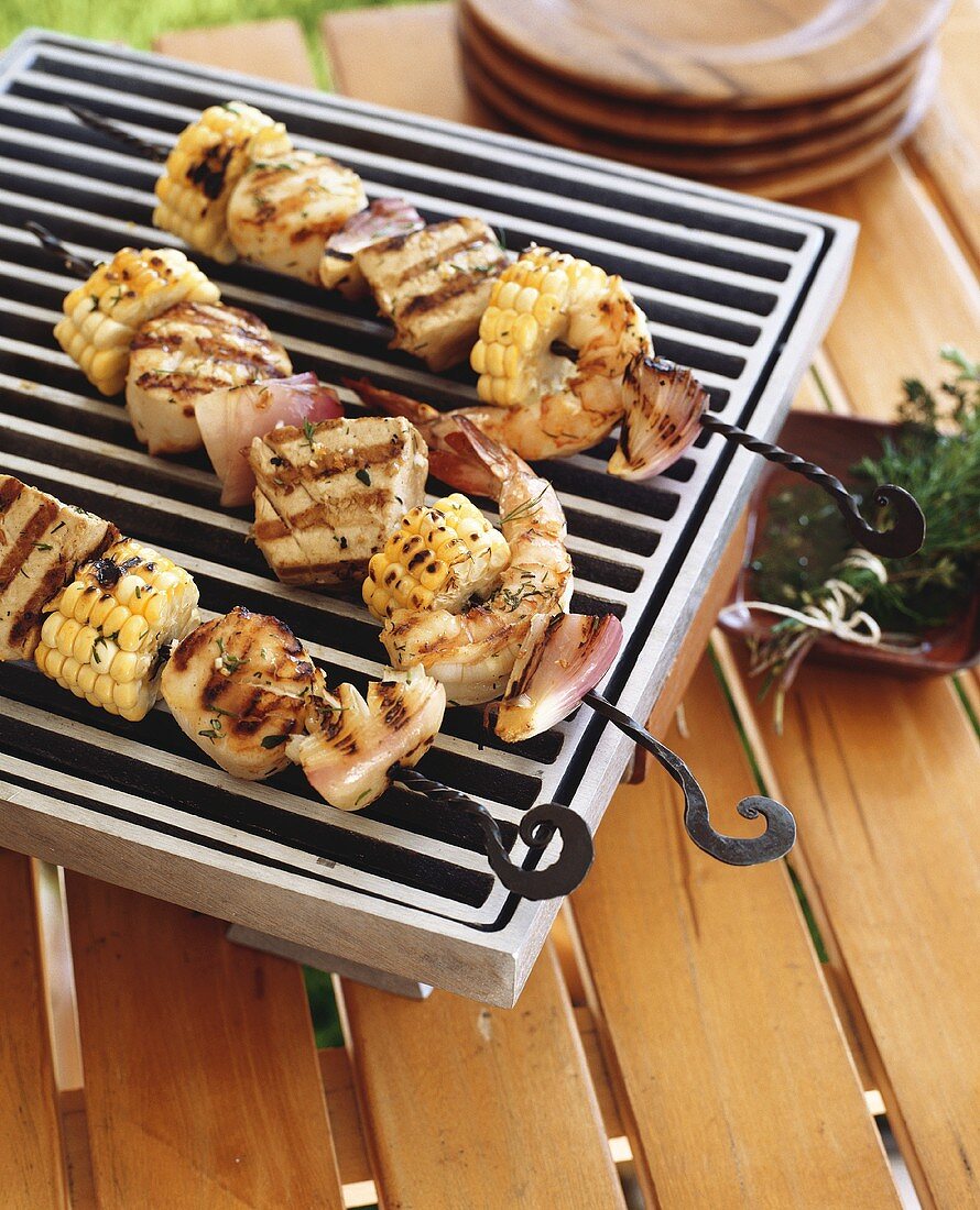 Skewered seafood and corncobs on barbecue