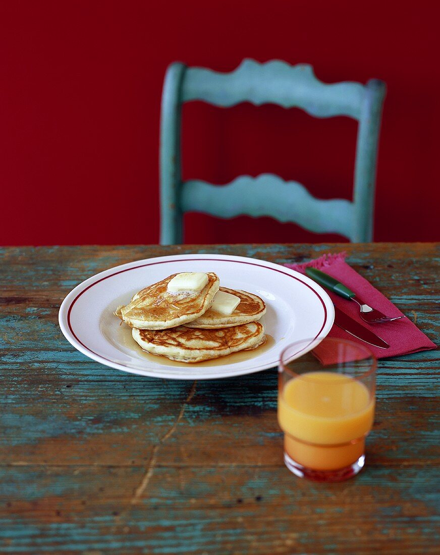 Pancakes mit Butter und Ahornsirup, Glas Orangensaft (USA)