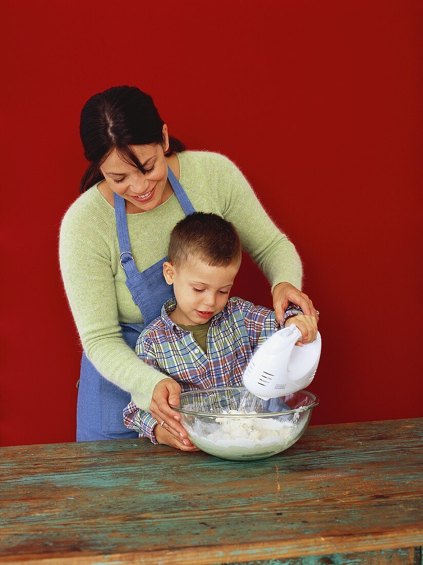 Woman and boy making pastry with electric mixer