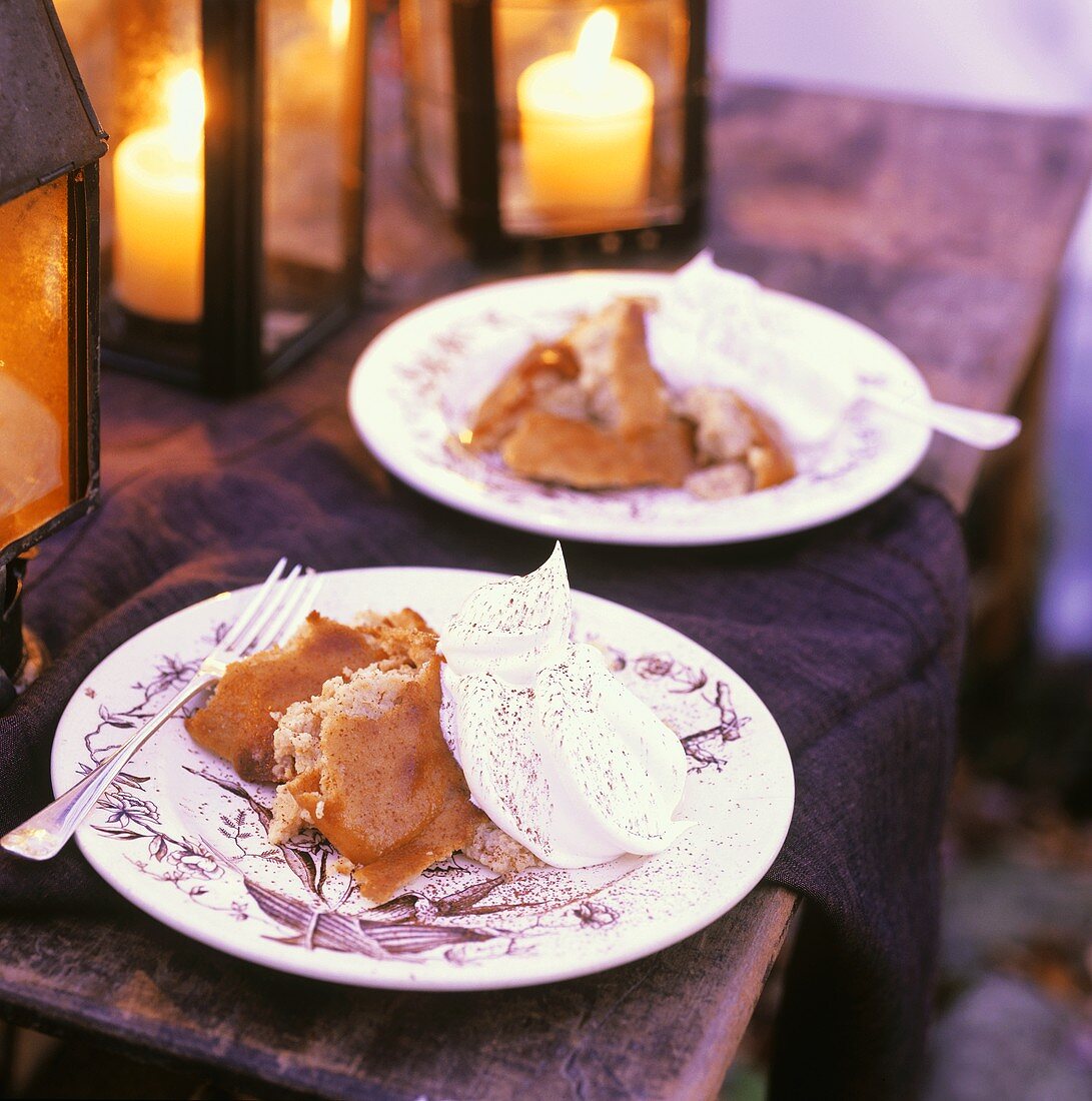 Plates of Steamed Indian Pudding with Whipped Cream on Outdoor Table; Lanterns