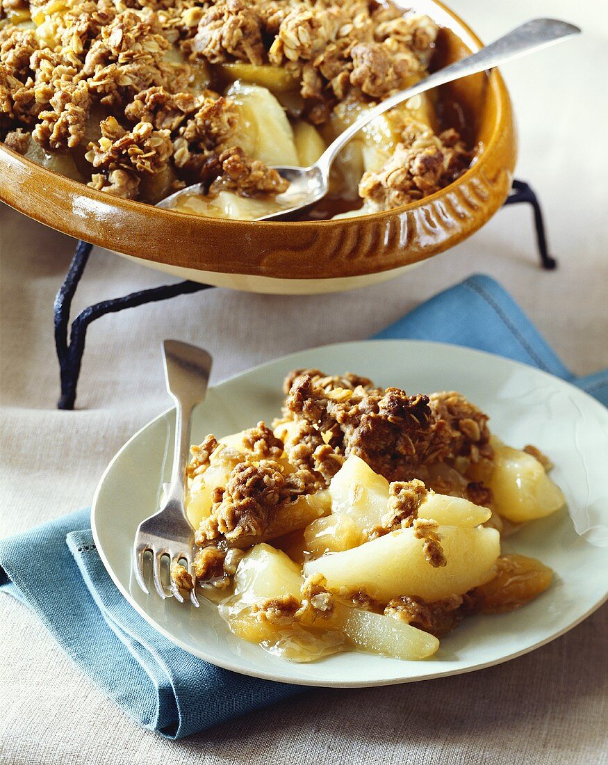 Pear Crisp with Granola Topping in Baking Dish with a Serving on a White Plate with a Fork