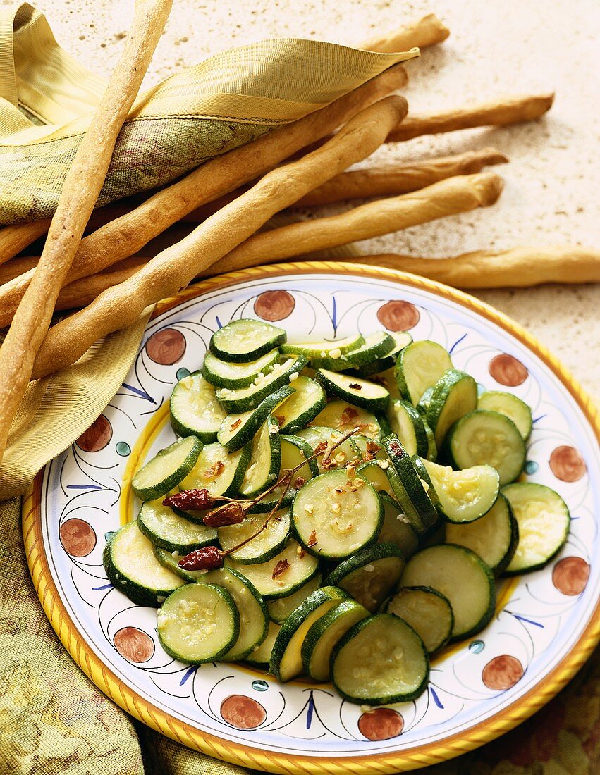 Side Dish of Sliced Sauteed Zucchini with Chili Pepper Flakes on Platter; Breadsticks