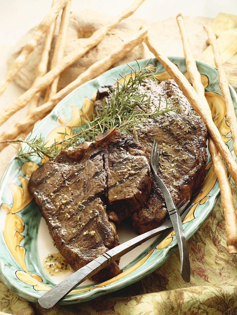 Steak Grilled with Garlic and Rosemary on a Platter with Breadsticks