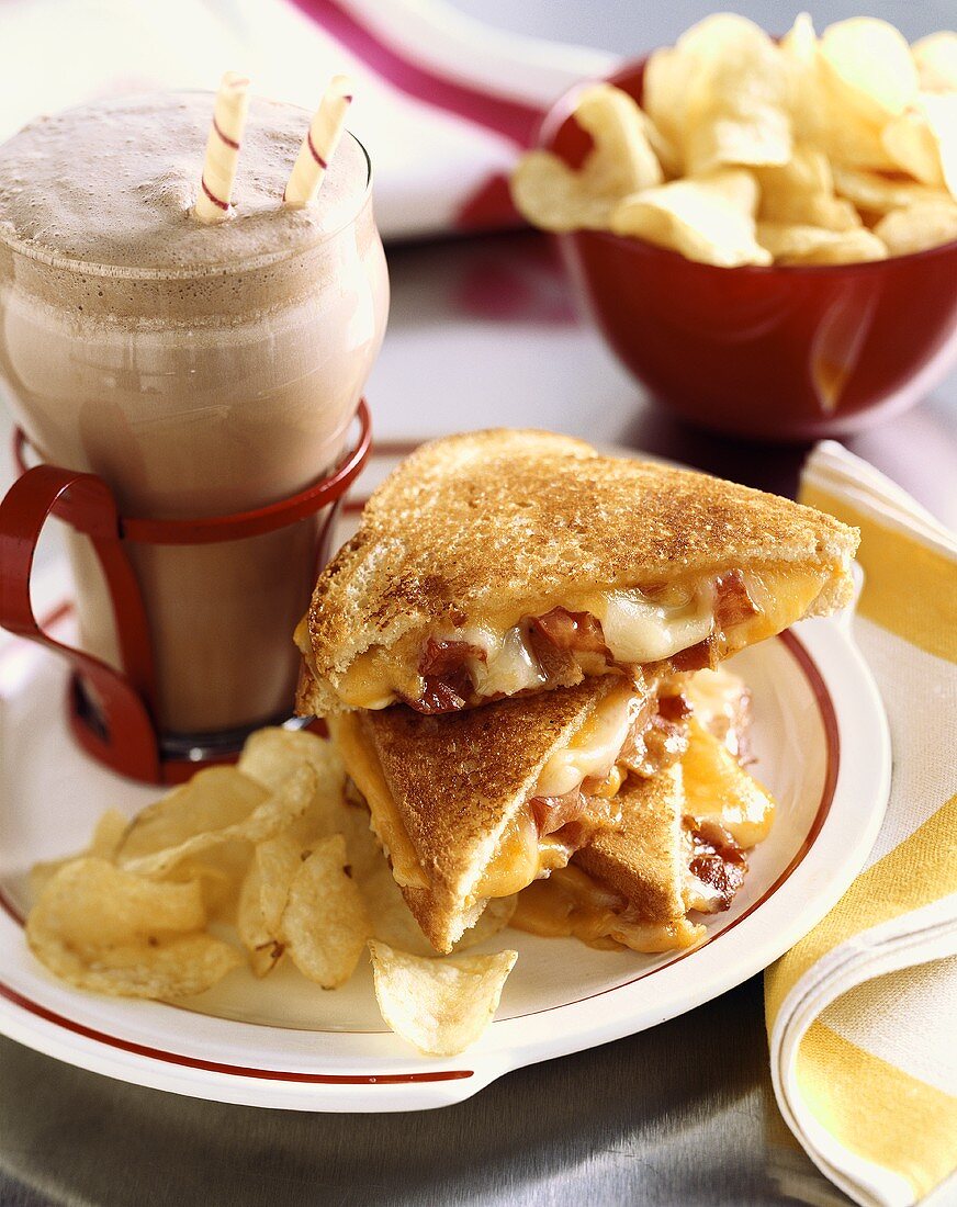 Cheddar and Swiss Grilled Cheese with Bacon on a Plate with Chips and a Chocolate Shake