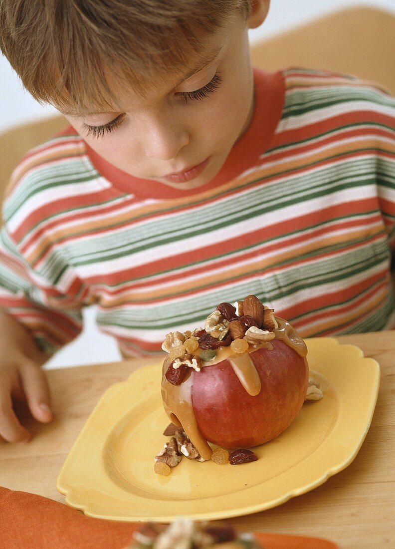 Junge isst Apfel mit Nussfüllung und Karamellsauce