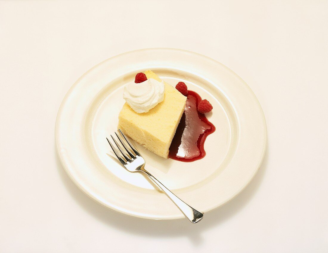 Piece of Poundcake with Whipped Cream and Raspberry Sauce on a White Plate with Fork