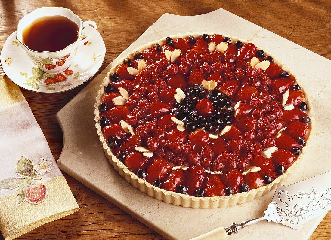 Berry Tart Made with Strawberries, Raspberries and Blueberries with Almonds; Cup of Tea