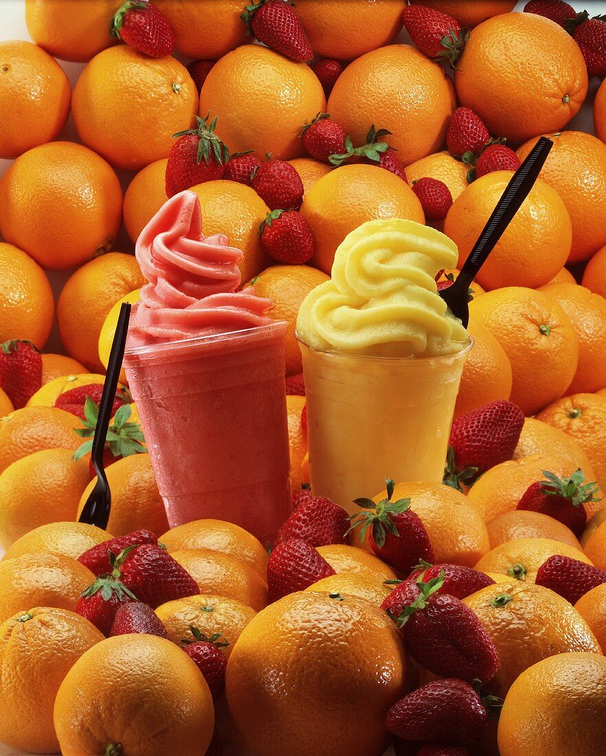 Orangen- und Erdbeersmoothies, umgeben von frischen Früchten