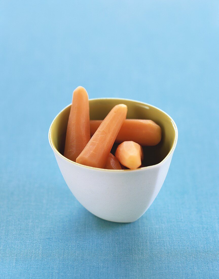 Peeled Baby Carrots in a White Bowl on a Blue Background