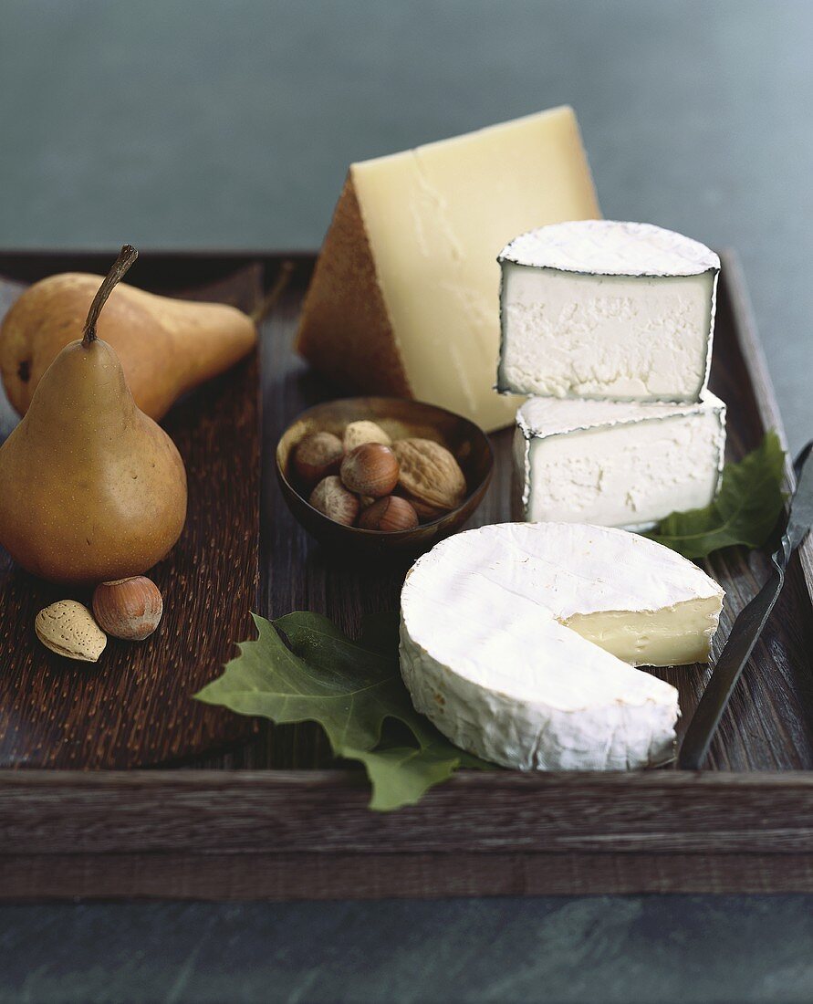 Assorted Cheeses (Brie, Humbolt Fog Goat Cheese & Grevere) with Nuts and Pears on a Rustic Wooden Tray