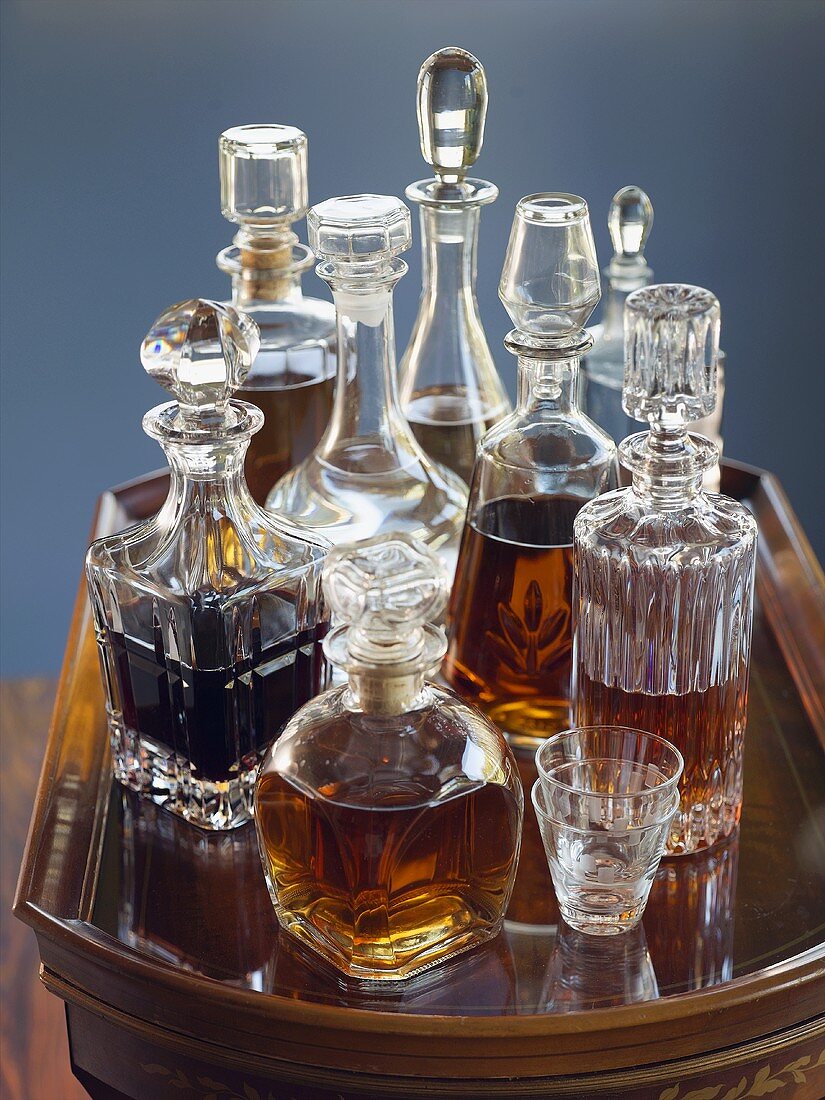 Assorted Decanters Filled with Assorted Liquors on a Glass Top Table