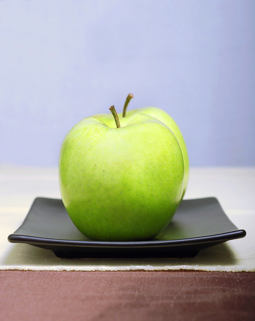 Two Granny Smith Apples on a Square Black Plate