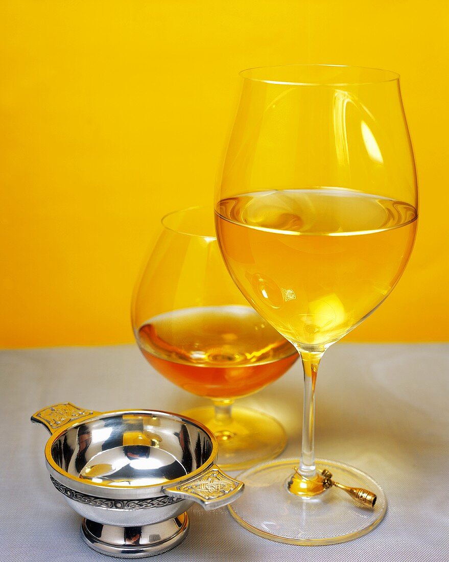 Glass of white wine and cognac with small silver bowl
