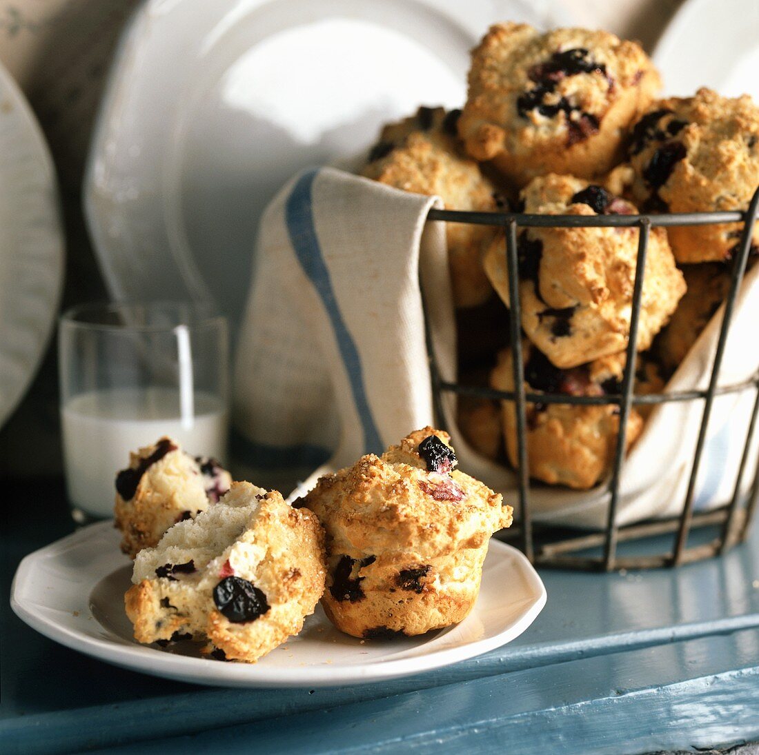 Blueberry Muffins in a Wire Basket and on a Plate with a Glass of Milk