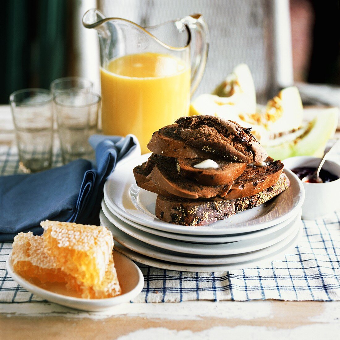 Frühstück mit Pumpernickeltoasts, Honig, Orangensaft, Melonen