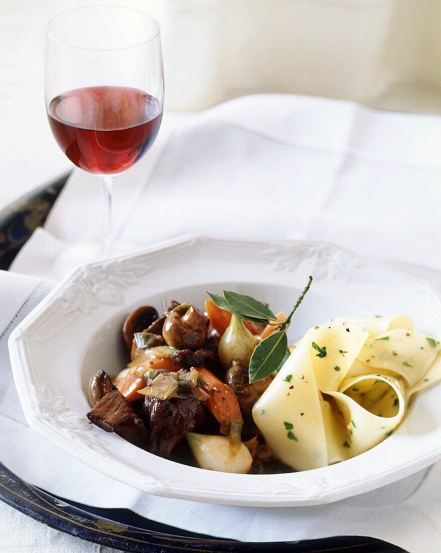 Lammragout mit Pappardelle und Glas Rotwein