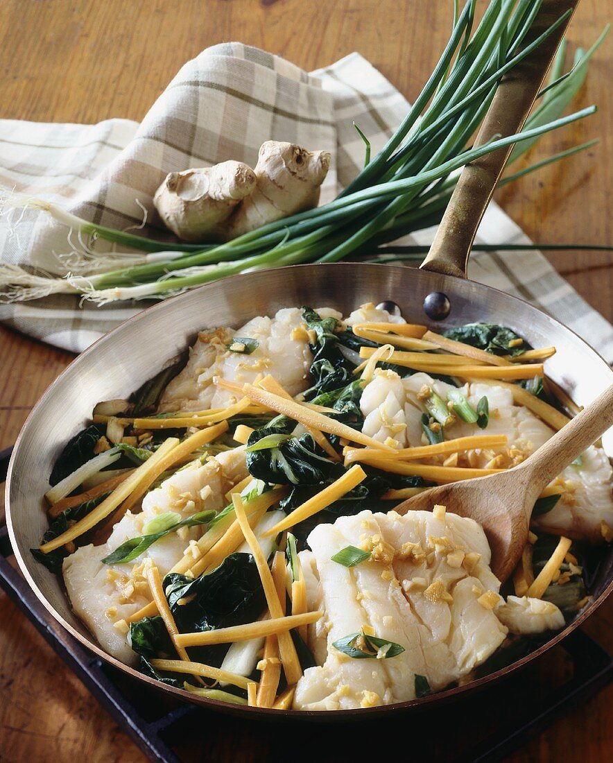 Fish fillets with ginger, carrots, spring onions in pan