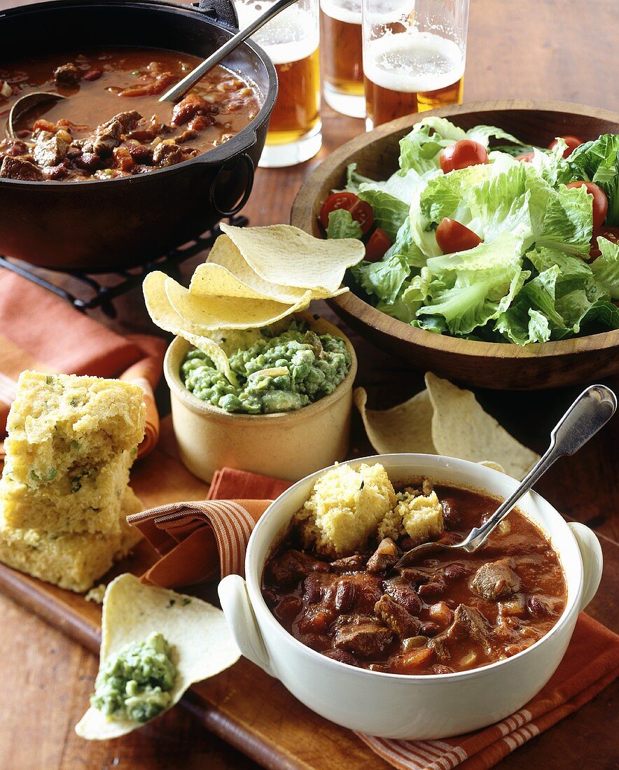 Chili mit Maisbrot, Chips, Guacamole, Salat und Bier