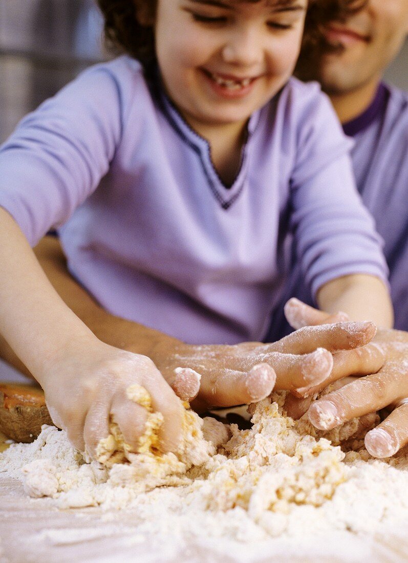 Girl kneading dough with her father