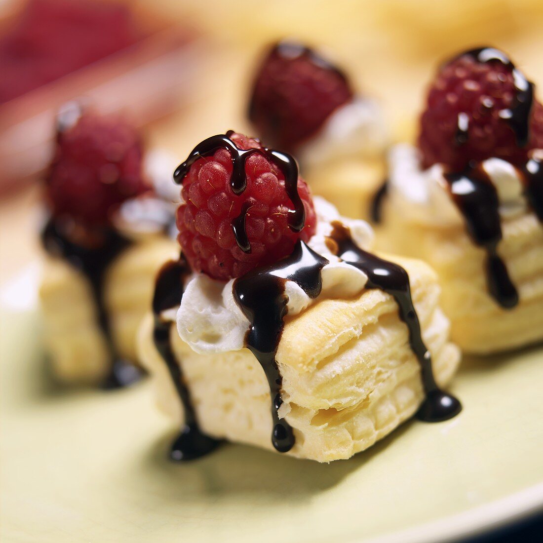 Puff pastry slices with cream, chocolate sauce & raspberries