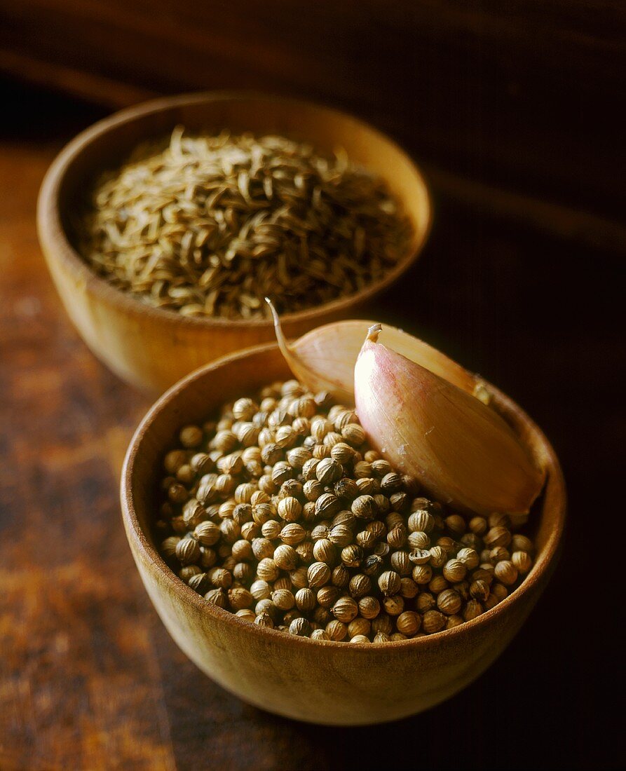 Coriander seeds with cloves of garlic in wooden bowl