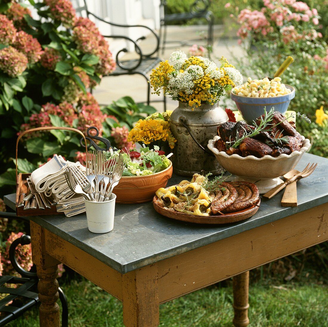 Buffet mit Grillgerichten und Salaten auf Gartentisch