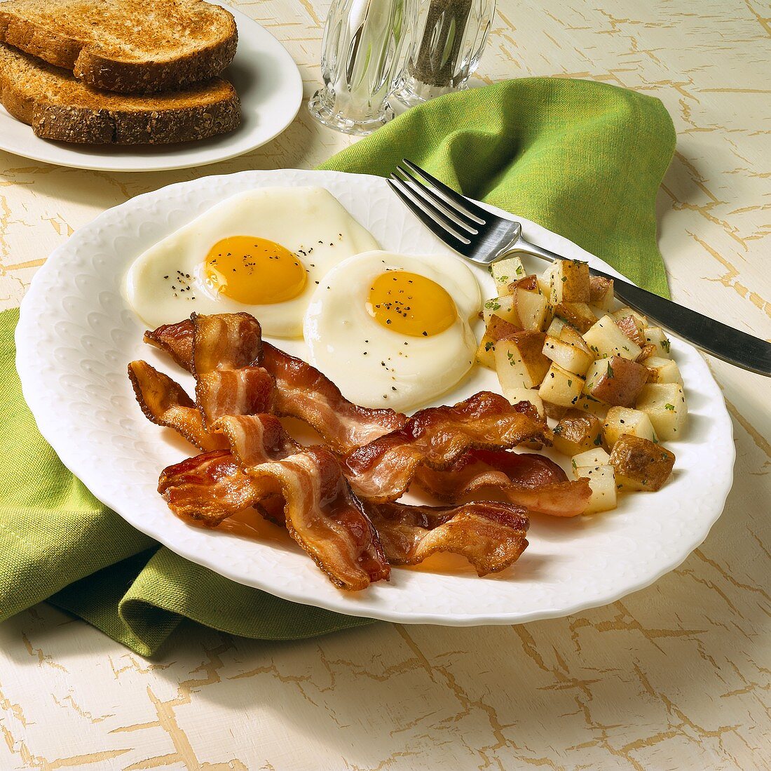 Breakfast Plate of Fried Eggs with Bacon and Home Fries on White Plate with Fork