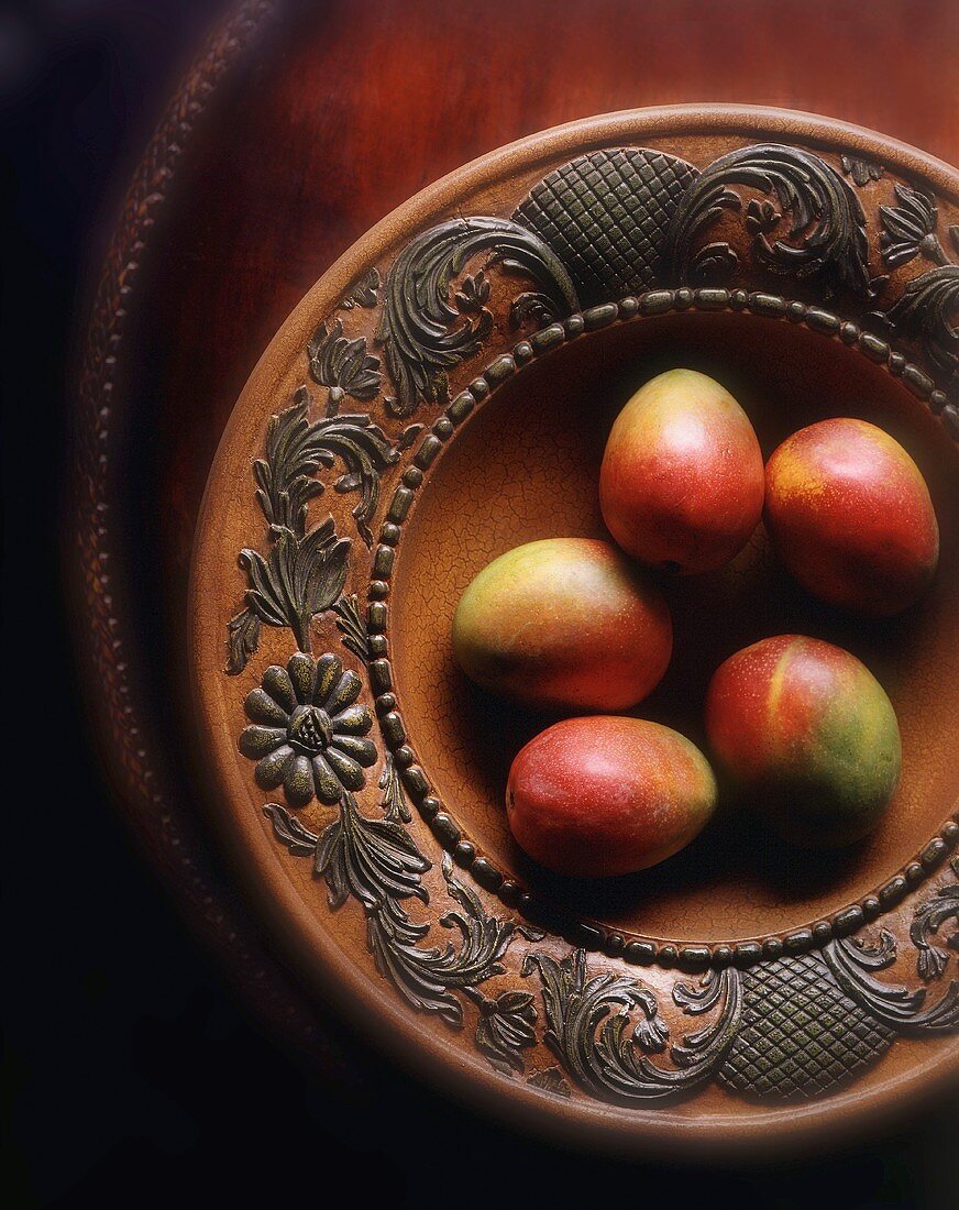 Fünf Mangos in einer Holzschale
