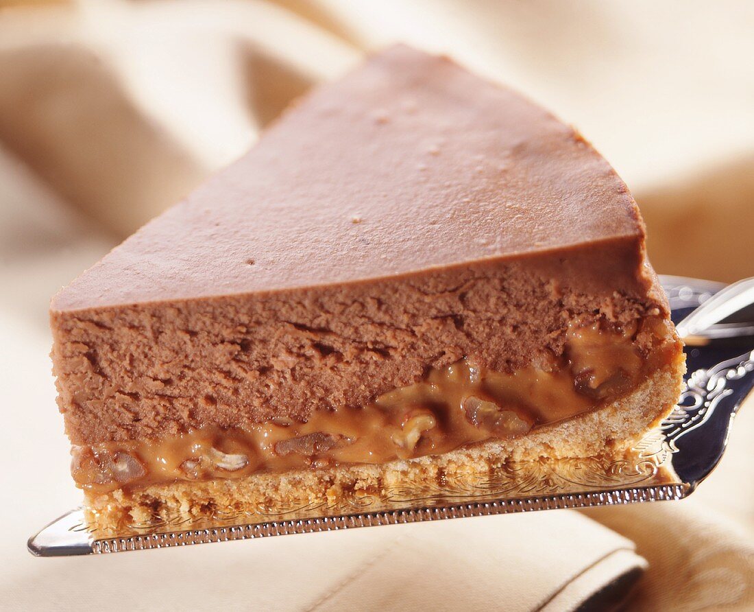 A slice of chocolate-caramel cheesecake on a cake slice