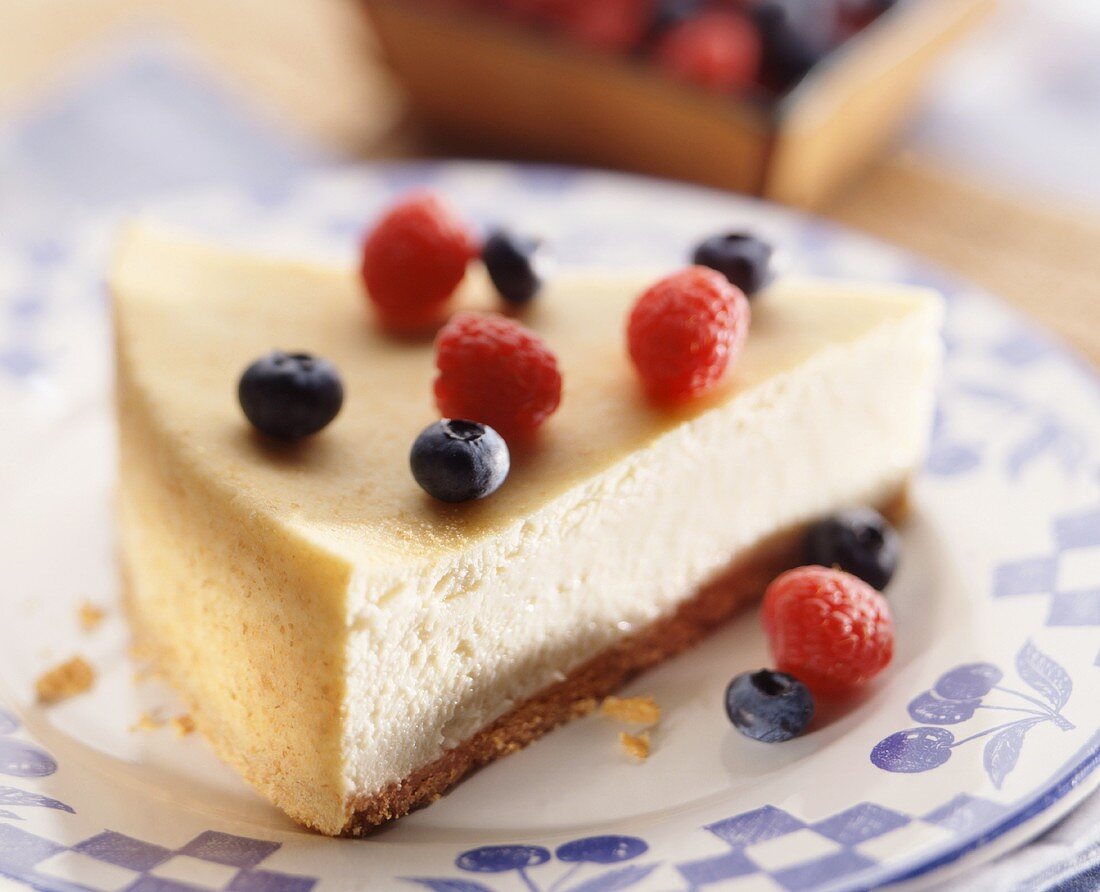 Ein Stück Käsekuchen mit Heidelbeeren und Himbeeren