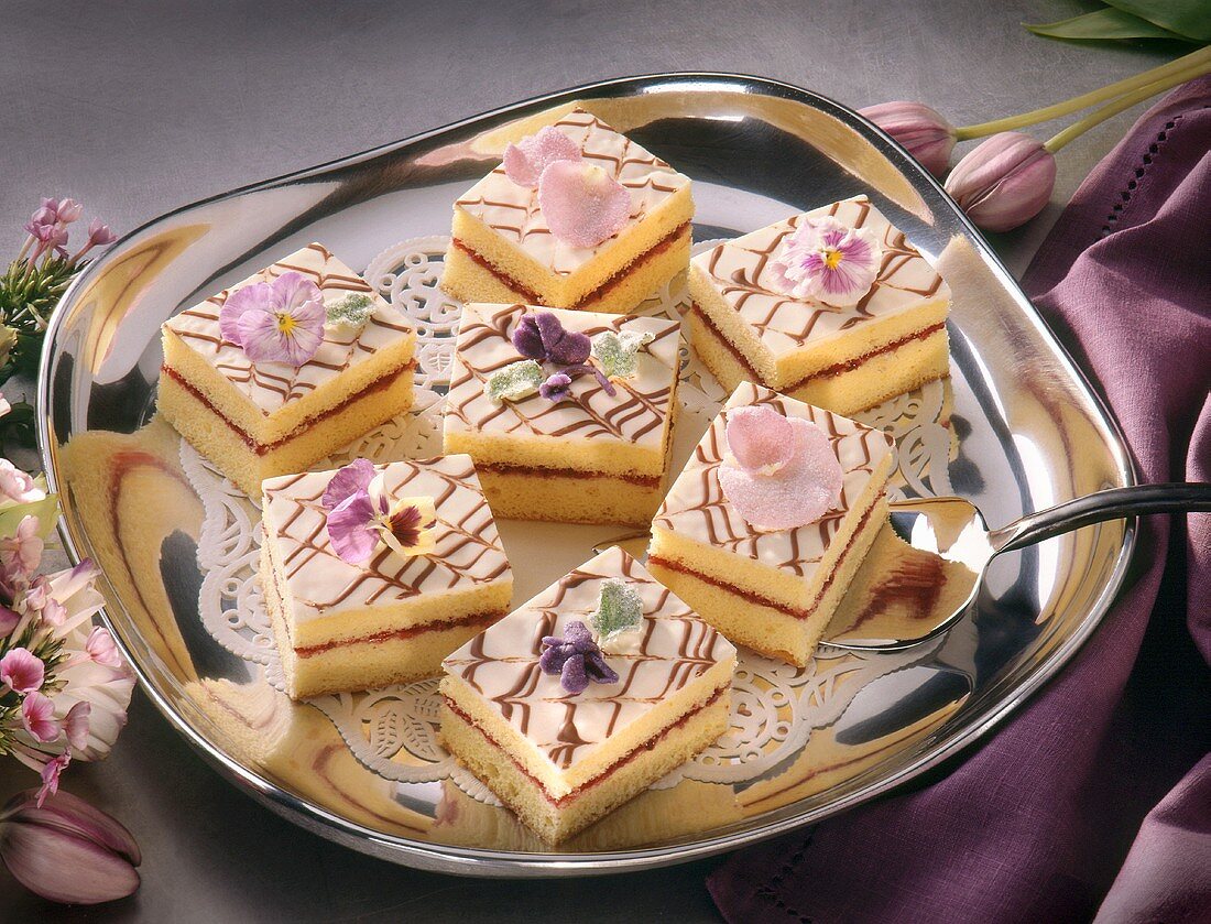 Zitronenschnitten mit Essblüten auf silbernem Tablett