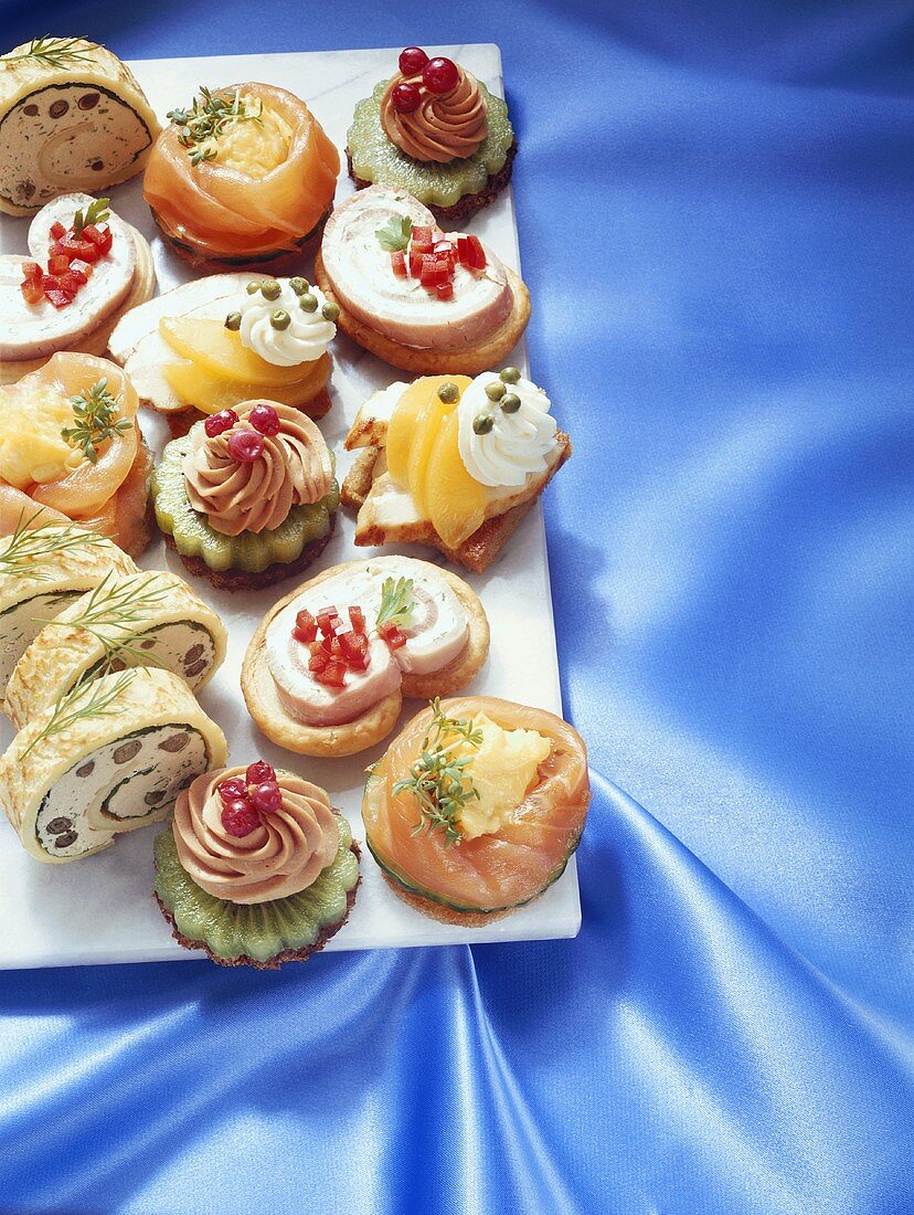 Elegant canapés on white board over blue fabric