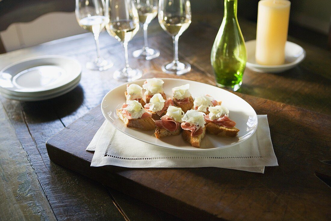 Crostini mit Rohschinken, Ricotta, Zwiebeln, Weissweingläser