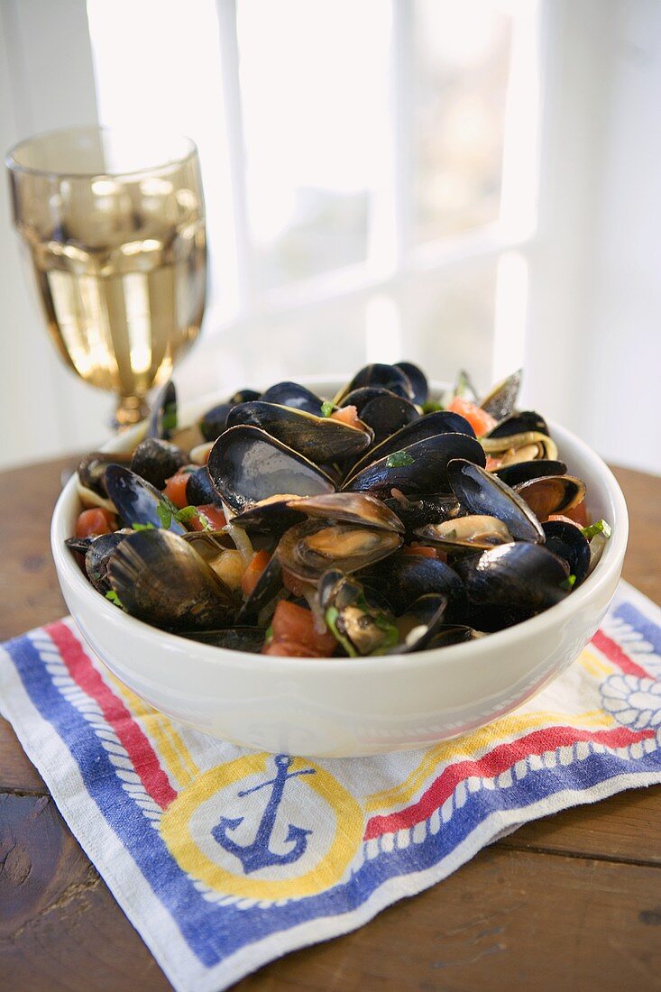 Steamed mussels in bowl, glass of white wine