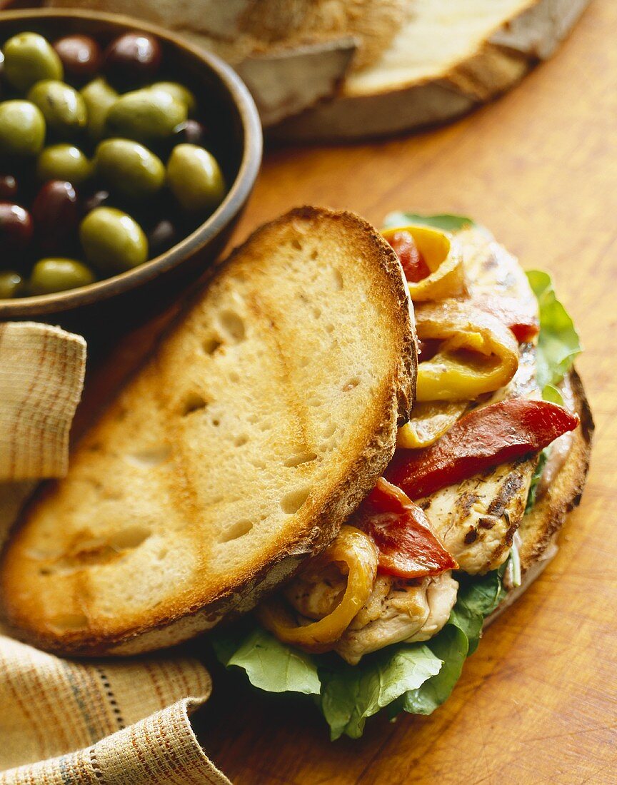 Grilled Chicken Sandwich with Roasted Peppers and Lettuce, Bowl of Mixed Olives
